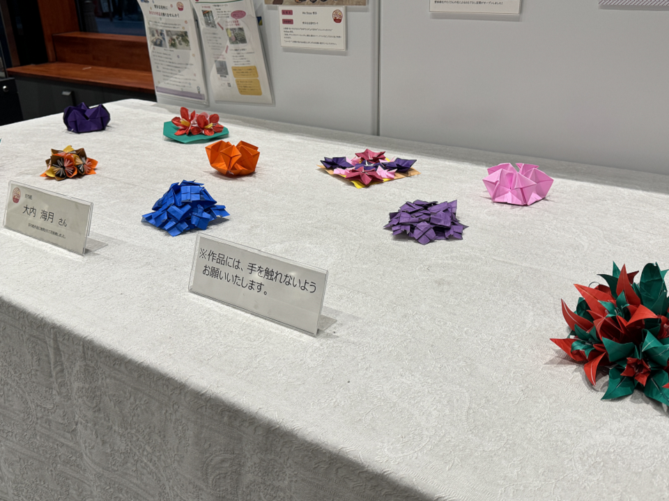 折り紙で作られた花が展示されている様子の写真。