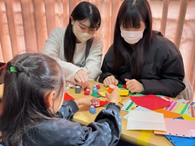 赤の折り紙でサンタクロースを作っている子どもの写真