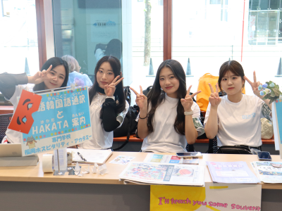 学生が屋内の通訳ブースでカメラに向かって笑顔を浮かべている写真