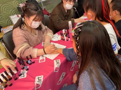 子どもが手の甲に色々な色のボディジュエリーを付けてもらっている写真