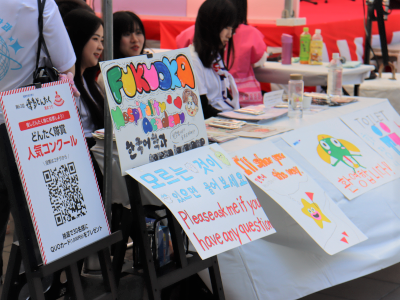 学生による通訳ブース（屋外）で、カラフルでポップな案内版が並んでいる写真