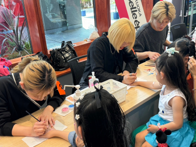 来場者の手に、にわか面のイラストをペイントしている写真