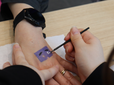 紫色のにわか面の、目の部分を描いている写真