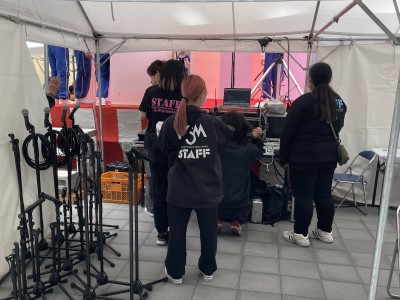 学生がステージ横テントで音響設備の操作をしている写真