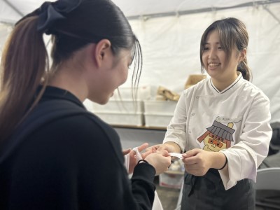 学生が商品を購入した人に説明カードを渡している写真