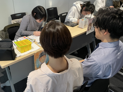 真剣に似顔絵に取り組む学生と、夫婦の写真