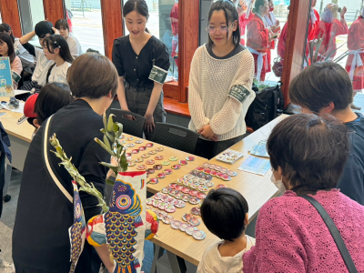 来場者が、机に並ぶ缶バッジを選んでいる写真