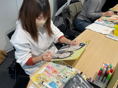 学生が絵具で似顔絵を描いている写真