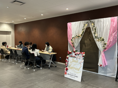 フォトスポットの隣で、カップルの似顔絵を描いている学生の画像