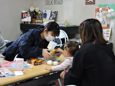 学生が子供に雪だるまの顔を描くためのペンを見せている画像