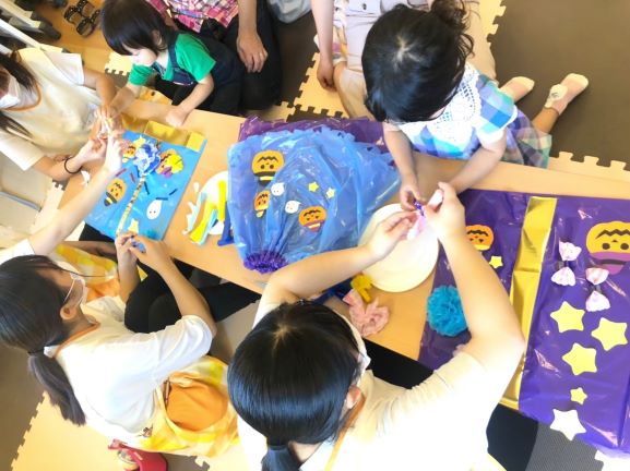 学生が地域の親子と一緒に衣装の飾りを作っている写真