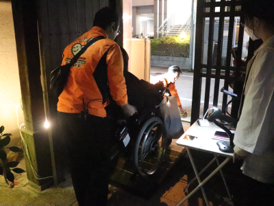 段差のあるイベント会場で、作業療法を学ぶ学生が、車椅子で来場されたお客様のサポートを行っている画像