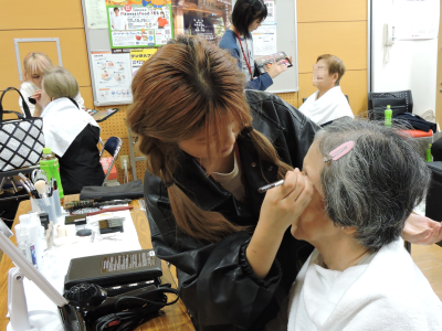 学生が参加者にメイクをしている写真