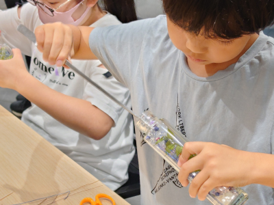 ピンセットで瓶に花を詰めている写真