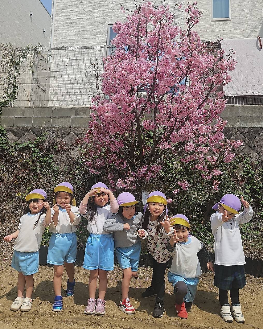 花が咲く木の前で笑顔を見せる子供たちの写真