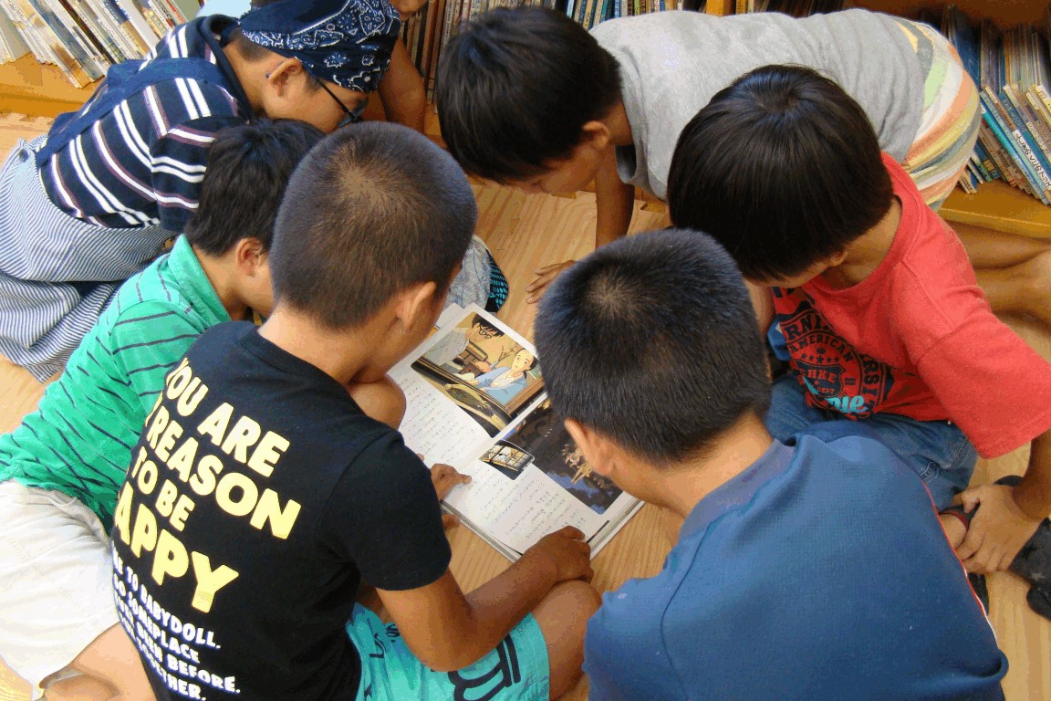 本を囲んでいっしょに読む子どもたちの写真