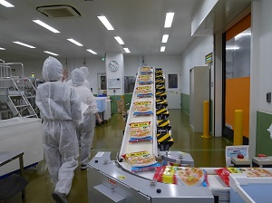 工場内の写真。皿うどんのパックがベルトコンベア上を流れている。