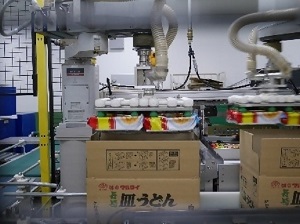 機械で段ボール箱に詰めている写真