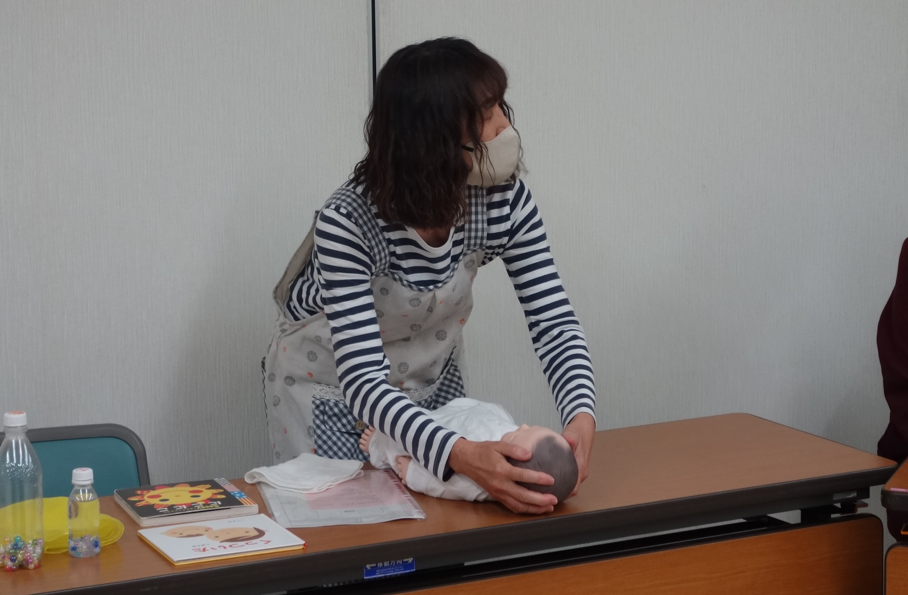 講師が赤ちゃん人形で親子遊びをしている様子