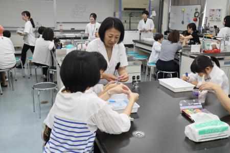 講師の新井先生が、各テーブルを回りながら参加者の様子を見ている様子