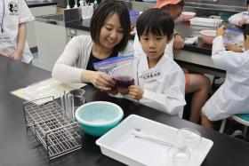 参加者の親子が協力して材料をもみ込みながら、色素を抽出している様子