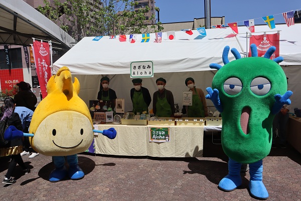 にっこりんわるもんがバザー店舗と写真をとった様子