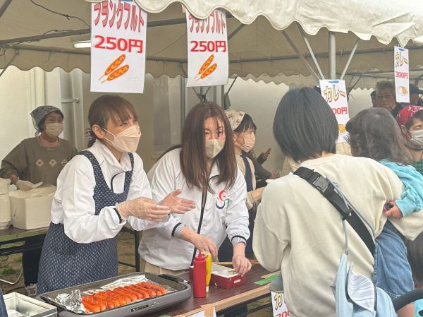フランクフルトの販売を手伝う区長(写真左)
