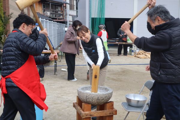 地域の人と息を合わせて餅をつく区長