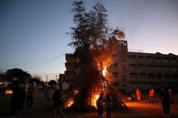 どんど焼きで炎が立ち上っていく様子を見守る地域の皆さんの写真