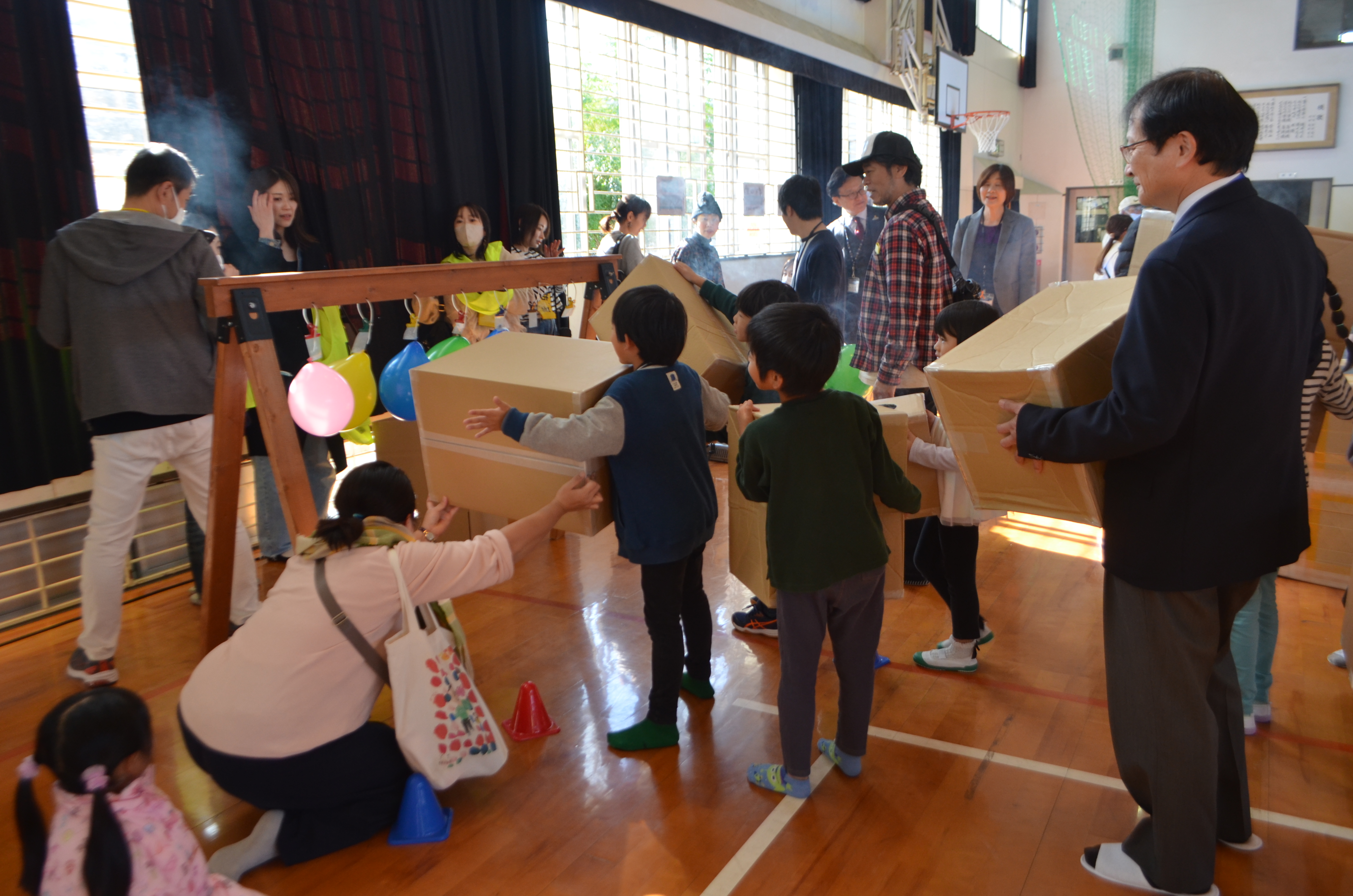 空気砲で風船落としに挑戦する子どもたちと区長の写真