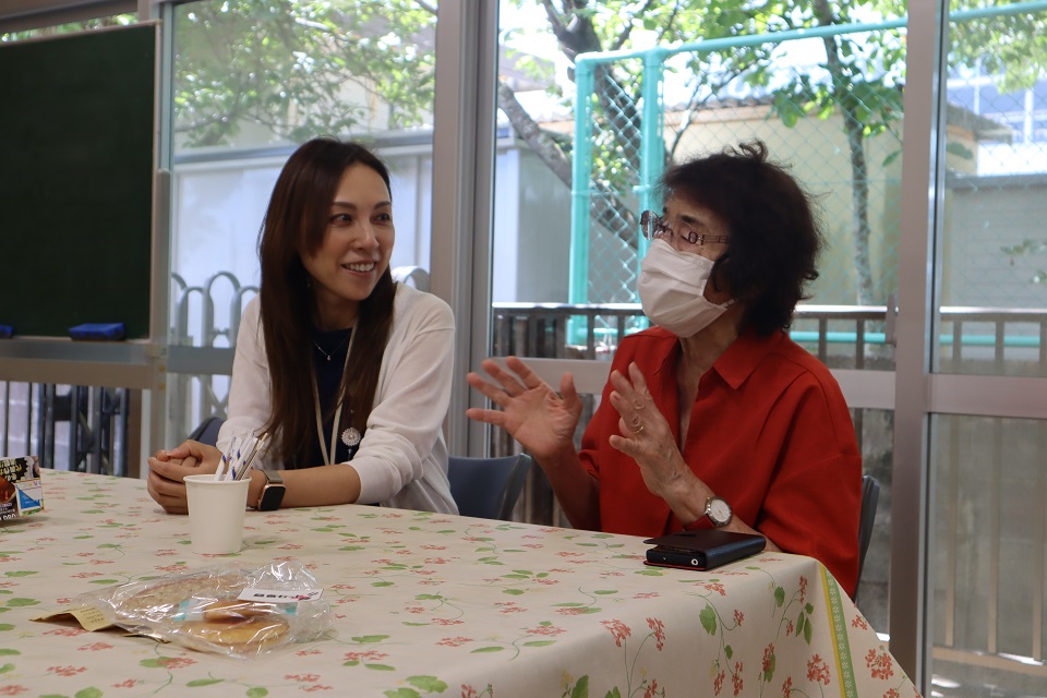 テーブルに座って地域の人の話に耳を傾ける大倉野区長（左）