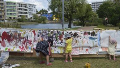子どもたちが大きな模造紙に自由にお絵描きをしている写真