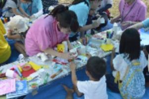 大学生と子どもたちがヨーヨー作りをしている写真