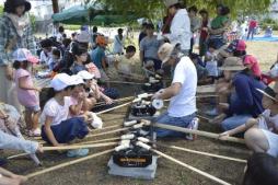 竹に先に刺したパンをかまどで焼いている写真