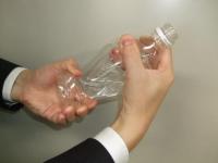 ペットボトルを手でつぶしている写真