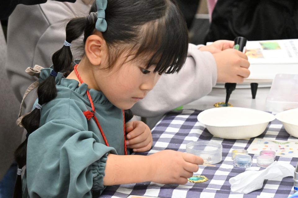 貝殻をつかってキーホルダーを作る子供