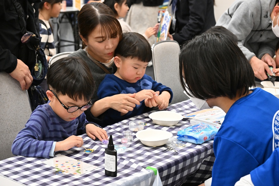 貝殻をつかってキーホルダーを作る子供たち