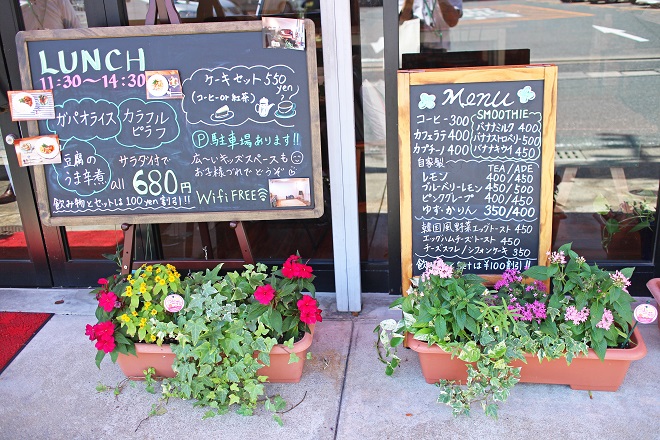メニューなどが書かれた看板とその前に並ぶプランターの写真