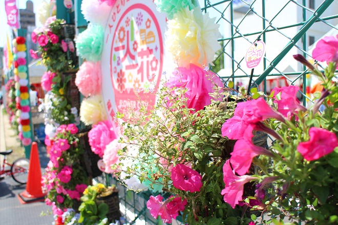 西新演舞台入口に飾られた花たちと大きな「一人一花」ロゴマークの写真