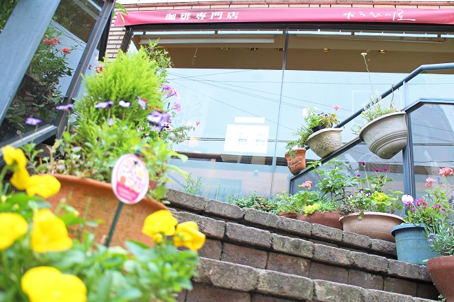 店舗前の階段から黄色い花とお店を見上げた写真