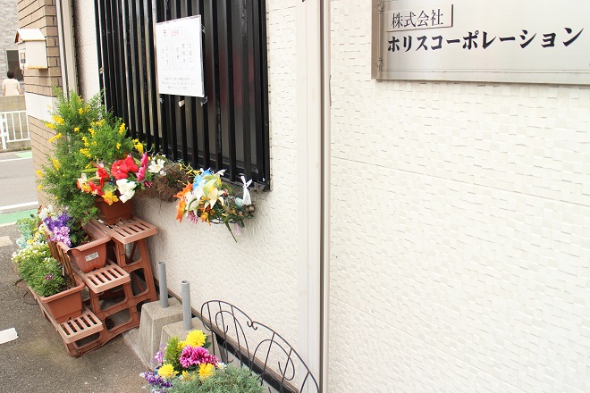 右上に「ホリスコーポレーション」，左側に階段状に置かれたプランターが見える写真