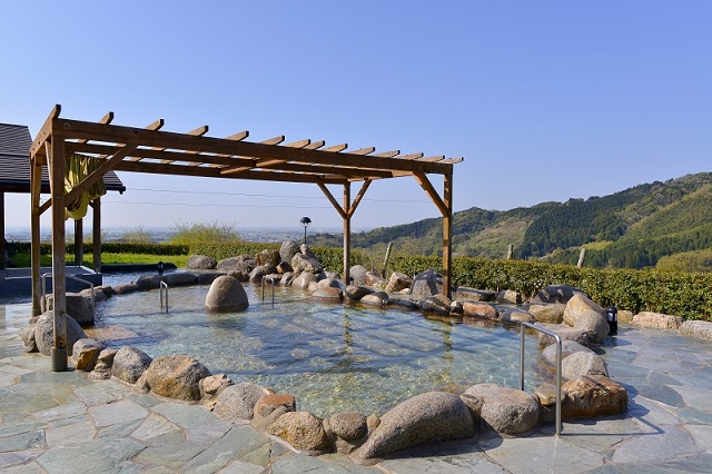 青空を背景にした山茶花の湯の露天風呂