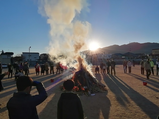 朝日を背景に煙が立ち上るどんど焼きの写真