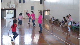 揃いのＴシャツを着て子どもとジャンケンする委員の写真