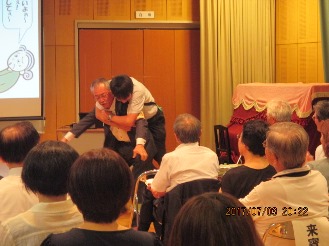 寸劇でけが人の背負い方を実演する講師の写真