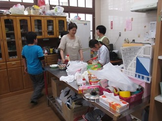 大人に見守られながら包丁を扱う子どもの写真