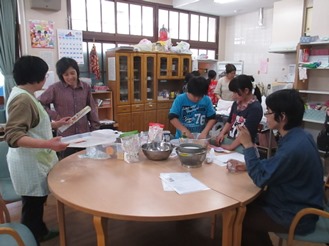 テーブルでピザ生地をこねる子どもたちの写真