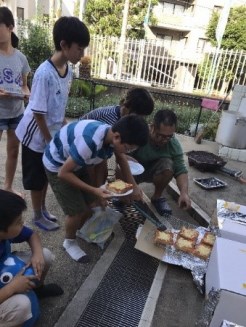 段ボールかまどからピザトーストを取り出す子どもの写真