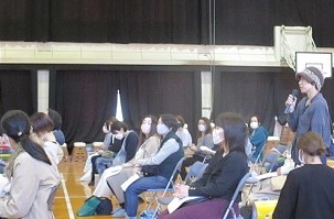 保護者がマイクを持って立ち、講師に質問をしている様子