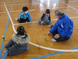 地域指導者の方とだるま落としをする子ども達
